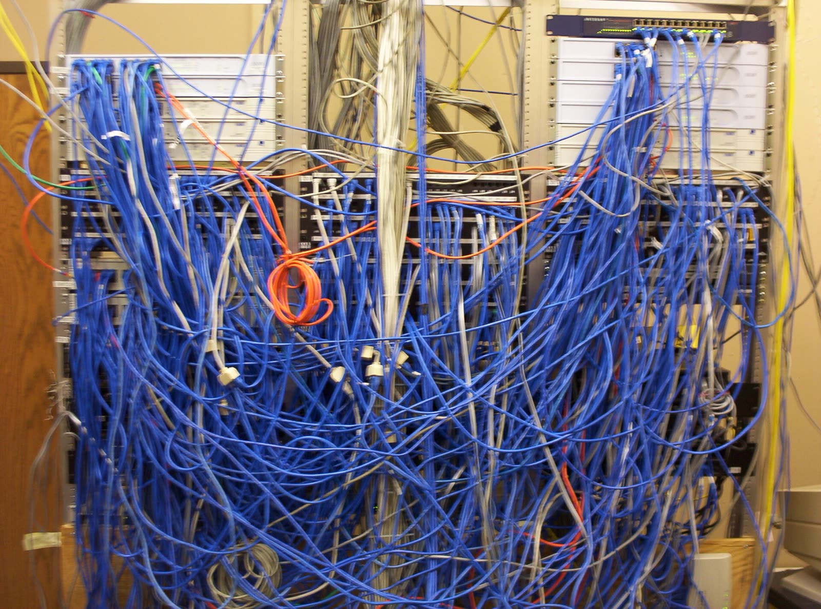 Armário de rede com centenas de cabos azuis embolados na frente dos switches